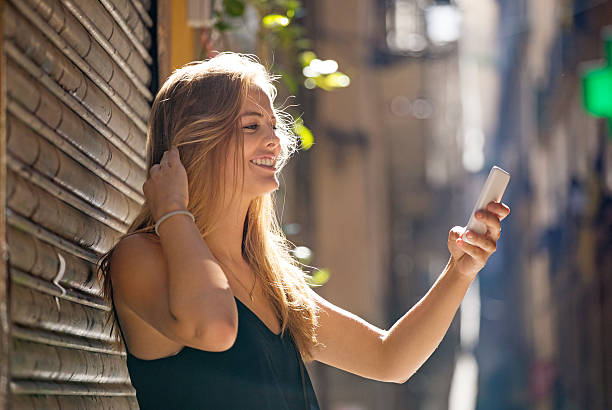 istock Beautiful blonde young woman using her smartphone on sunny day 621127266