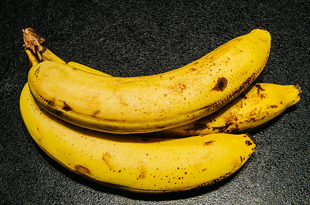 istock Slightly browned bananas on textured black background 621127976