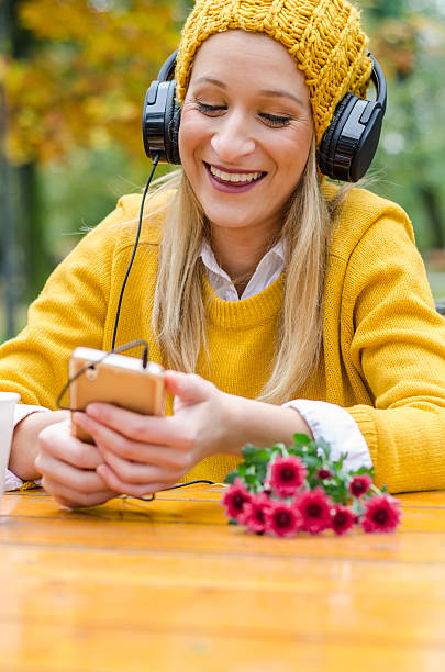 une fille hipster ou une adolescente écoute de la musique sur un mobile - autumn table setting flower photos et images de collection