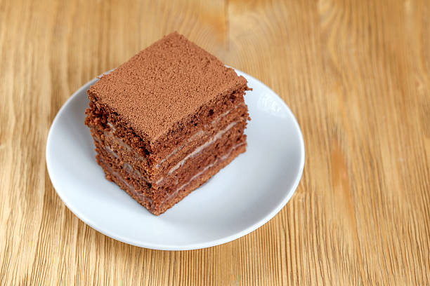 istock Piece of chocolate cake in white plate on wooden table 621135538