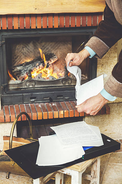 istock Hands tear sheets in bathrobe in front of burning fireplace 621138134
