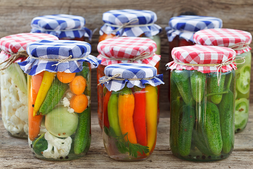 Jars of pickled vegetables on wooden table. Marinated food.