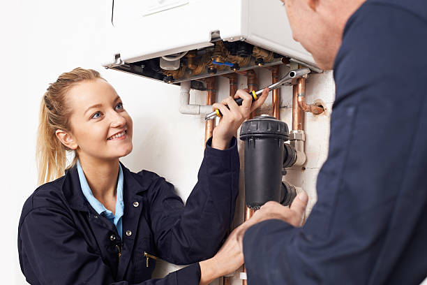 femme en formation plombier travaillant sur chaudière de chauffage central - trainee education construction worker plumber photos et images de collection