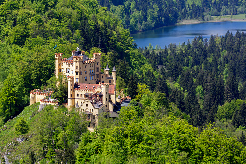 Fussen, Germany - May 18, 2013: The Hohenschwangau Castle that is a nineteenth century palace in southern Germany on Bavarian land. The massive building of the castle that is on top of the hill among greenery and of the close geographical proximity of a lake.