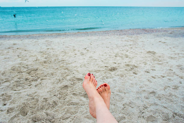 istock woman's feets on the sea shore 621145014