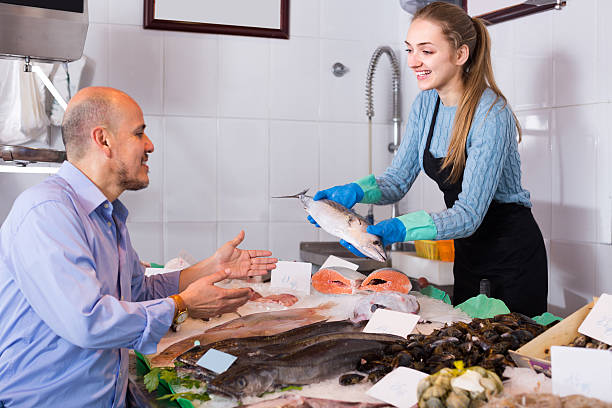 istock Friendly shopgirl offering fish to client 621145926