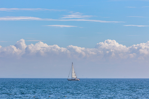 Yacht in the centre with white sails in the blue open sea