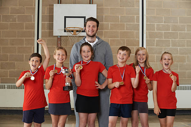 vitoriosa escola equipa com medalhas e troféus no ginásio - child basketball sport education imagens e fotografias de stock