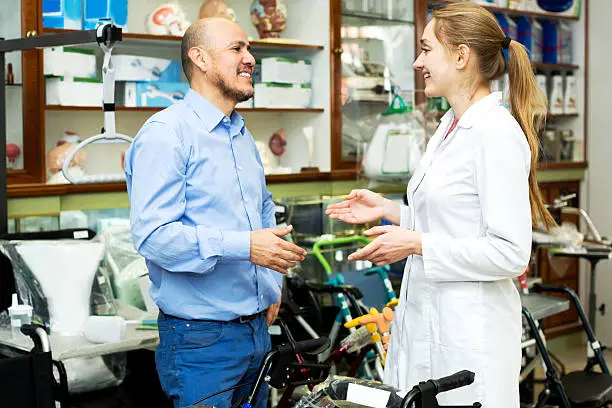 Photo of Female consultant offering wheelchair to mature customer