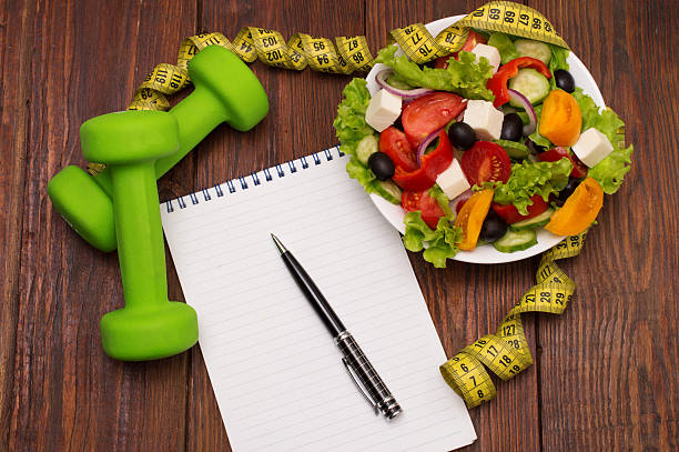 istock Dumbbell, vegetable salad and measuring tape on rustic wooden table. 621227788