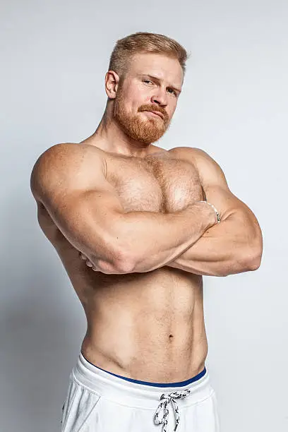 young caucasian muscular bearded man isolated on studio background