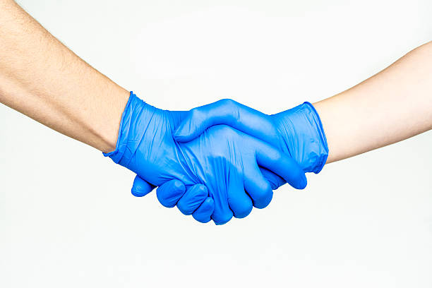 Handshake with blue medical gloves, stock photo