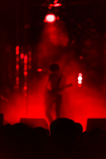guitar player on stage during a music concert; with colorful stage lights (defocused)