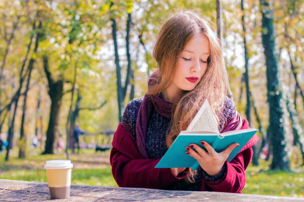 istock Woman reading book in a park 621234038
