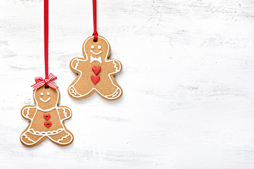 Happy Gingerbread cookie people hanging on white background.