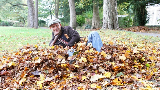 smiling mature man lying on ground in autumn park