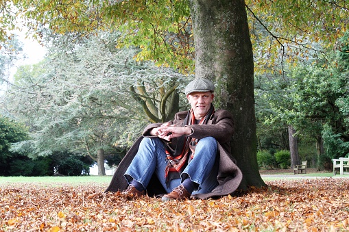 Mature man sitting under tree on an Autumn day