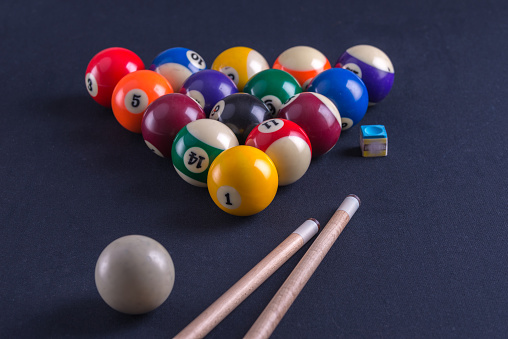 Blue billiard table with balls and two cues.