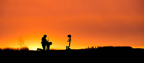 istock Soldier kneeling in front of a grave- sunset, copy space 621237236