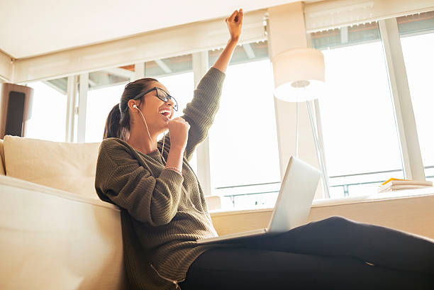 young woman cheerfully singing in her living room - young adult technology beautiful singing imagens e fotografias de stock