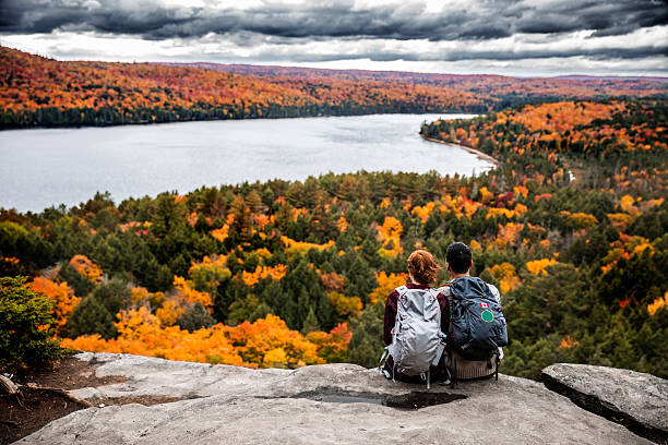 pareja joven haciendo senderismo en la montaña y relajante mirando a la vista - autumn women park forest fotografías e imágenes de stock