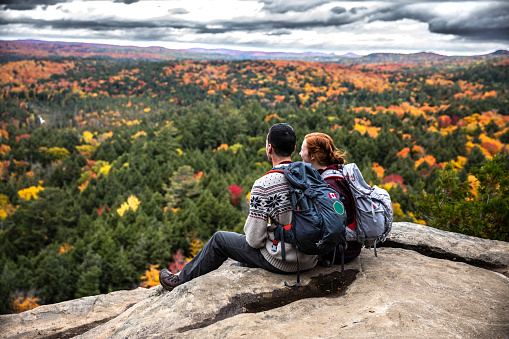Young couple hiking in mountain and relaxing looking at view in the Algonquin Park, Ontario - Canada.