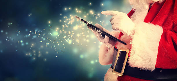 Santa Claus using tablet in snowy night stock photo