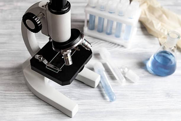 istock microscope in the laboratory with test tubes on wooden background 621243860