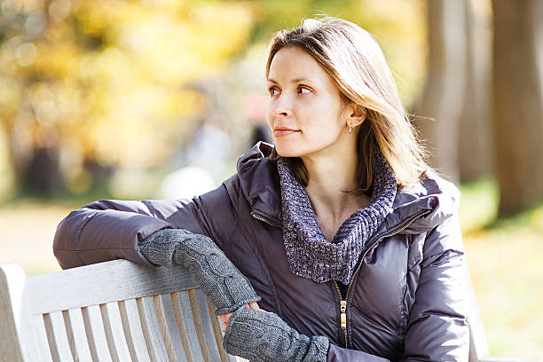 istock pretty woman sitting on a bench in the park 621251114