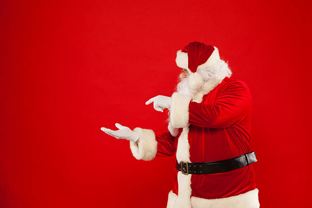 istock Santa Claus pointing in blank a place, red background 621254576