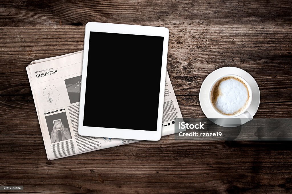 Daily newspaper, coffee and tablet with a blank screen. Daily newspaper and tablet with a blank screen on the wooden table. Above view. Text generated Lorem ipsum. Magazine - Publication Stock Photo