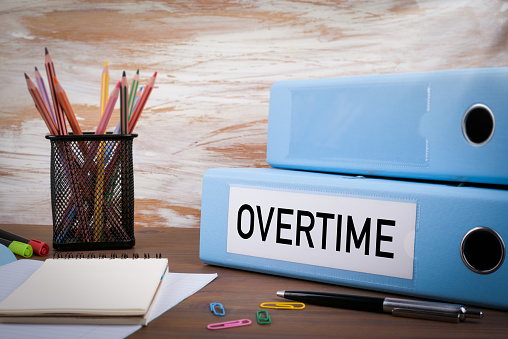 Overtime, Office Binder on Wooden Desk. On the table colored pencils, pen, notebook paper