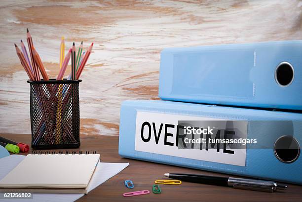 Overtime Office Binder On Wooden Desk Stock Photo - Download Image Now - Working Late, Paying, Excess
