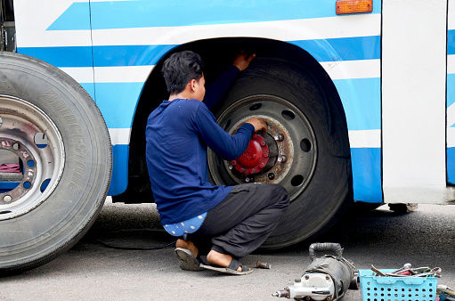 Mahasarakham, Thailand - May 3, 2015: Thai mechanic people repairing and fix change wheel tire of bus broken and explosion on the road at countryside.