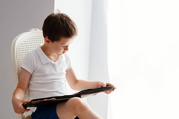 istock Little 7 years old boy browsing old photo album. 621263802