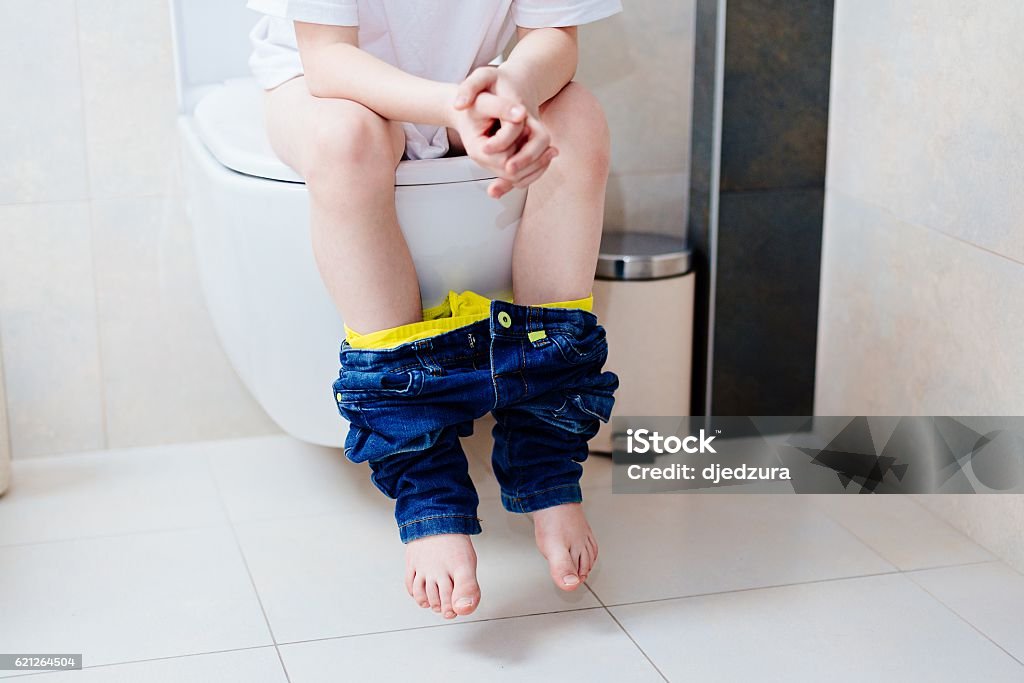 Little 7 years old boy on toilet. Little 7 years old boy on toilet. Low view on his legs Child Stock Photo