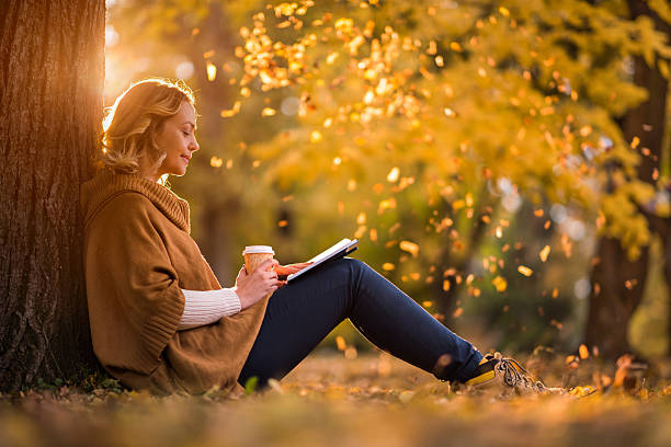 Relaxed woman reading a book in autumn day.