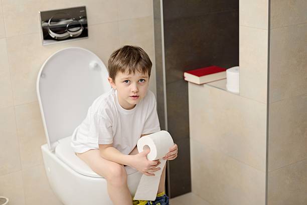 istock Little 7 years old boy sitting on toilet. 621264626