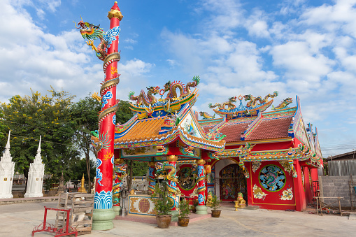 Red public shrine with golden dragon statue in chinese style on blue sky background at Thailand