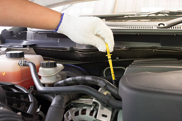 Auto mechanic checking oil level in a car engine