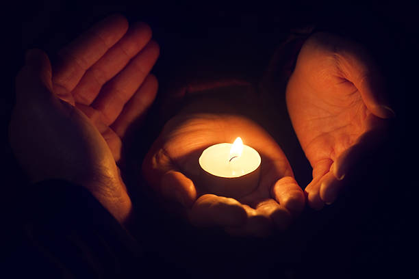 istock hands holding a burning candle in dark 621271114