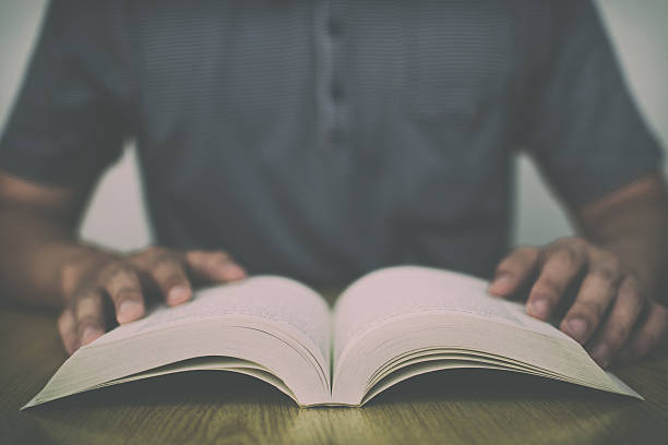 istock Man reading book on wooden table with vintage filter background 621273260