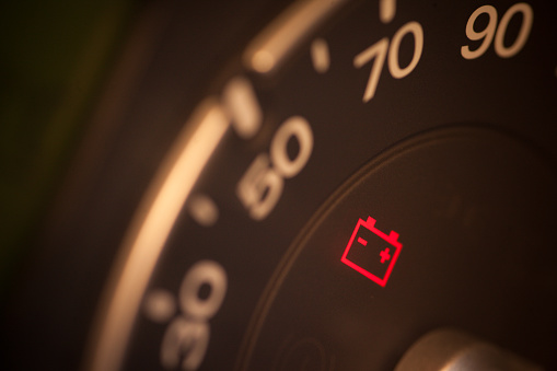 Close up shot of a car's dashboard with the battery icon lit.