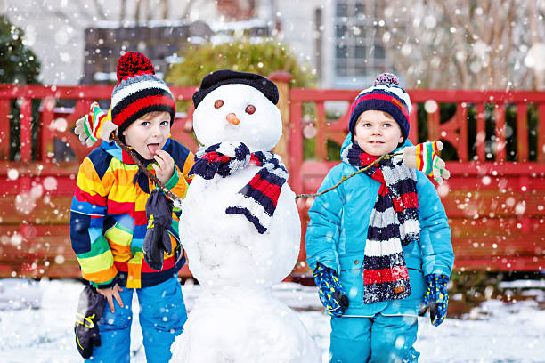 istock Two little siblings kids boys making a snowman 621350322