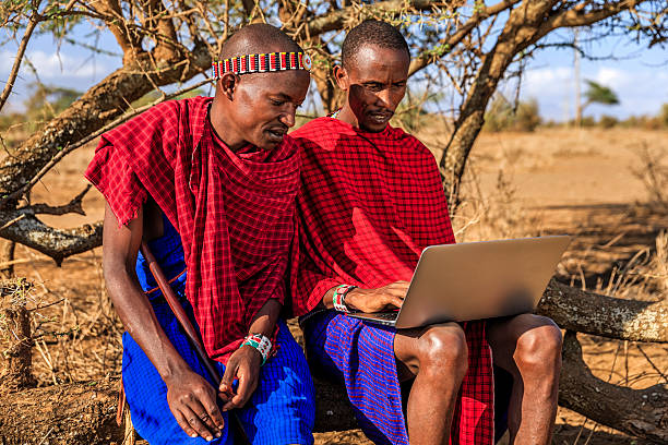 Warrior from Maasai tribe using laptop, Kenya, Africa African warrior from Maasai tribe using laptop, central Kenya, Africa. Maasai tribe inhabiting southern Kenya and northern Tanzania, and they are related to the Samburu. warrior person photos stock pictures, royalty-free photos & images