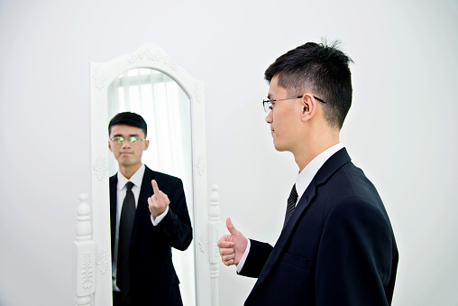 Bipolar disorder businessman looking at mirror with another himshelf. Agree or conflict?