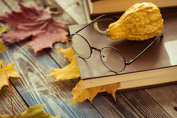 istock Eye glasses with book and autumn leaves on table 621353658