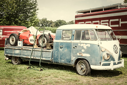 Jüchen, Germany - August 5, 2016: Porsche Formula racing car on a Transporter 1960s Volkswagen Bus flatbed pick up double cab with beautiful patina. There is a Porsche racing truck parked in the background. The car is on display during the 2016 Classic Days at castle Dyck. 