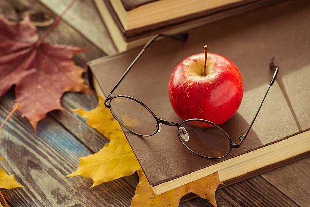 istock Eye glasses with book and autumn leaves on table 621353830