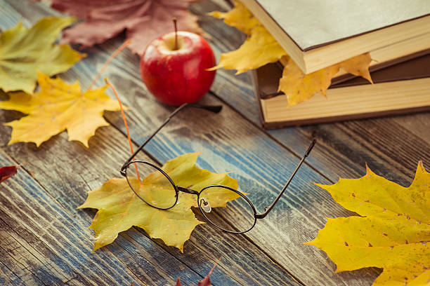 istock Eye glasses with book and autumn leaves on table 621353918